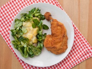 Un plato que contiene pollo empanizado con una ensalada