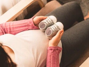 Mamá embarazada de un niño arcoíris cogiendo unos zapatitos.