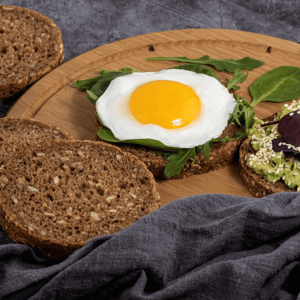 Huevo sobre pan de linaza y salsa cremosa de albahaca