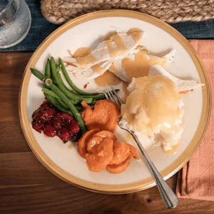 Un plato que contiene vegetales, pure de papa y pollo