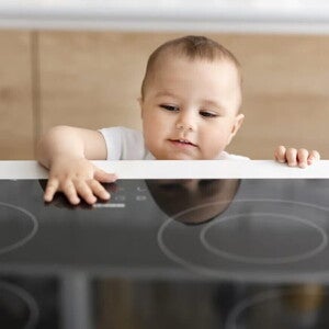 Bebé alcanzando la superficie de una cocina eléctrica