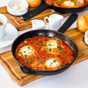 Huevos cazuelas en salsa de tomate dentro de una sarten de color negro