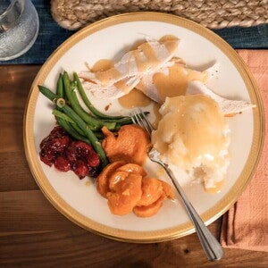 Un plato que contiene vegetales, pure de papa y pollo