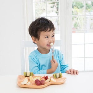 Un niño comiendo fruta en la cocina.