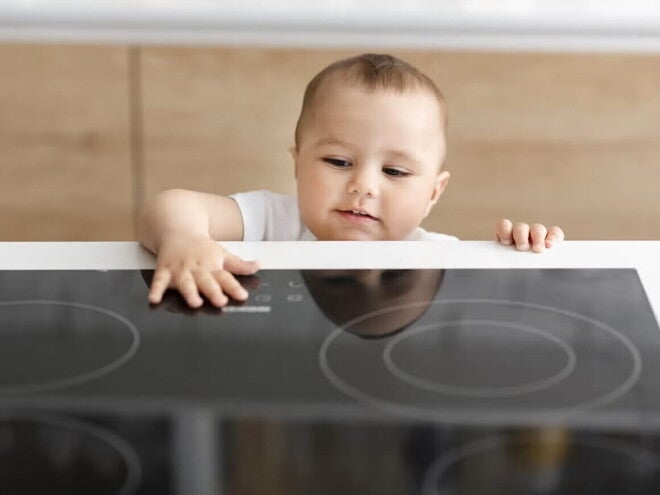 Bebé alcanzando la superficie de una cocina eléctrica