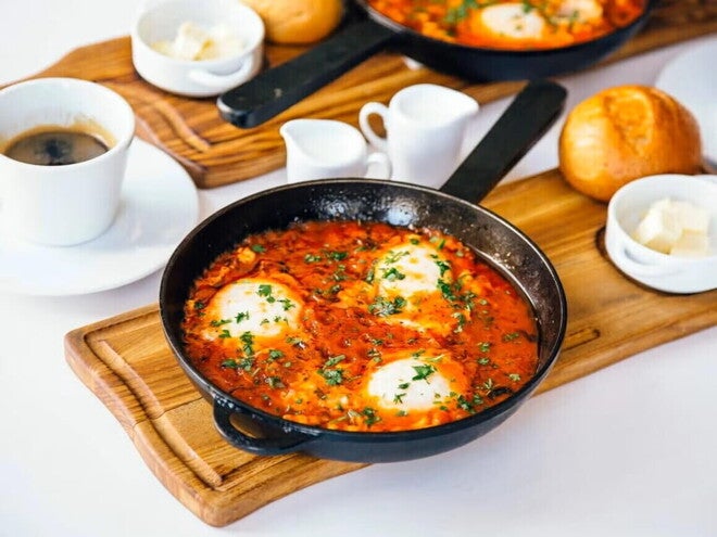 Huevos cazuelas en salsa de tomate dentro de una sarten de color negro