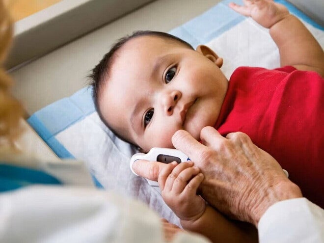 Profesional de salud midiendo la temperatura de un bebé