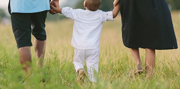 Papá y mamá viendo cómo camina la hija.